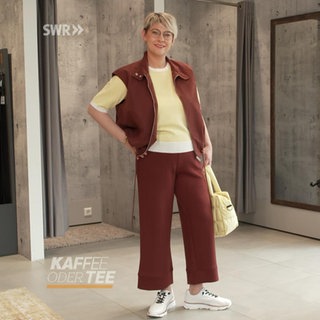 Eine Frau präsentiert Frühjahrsmode neben einer Vespa