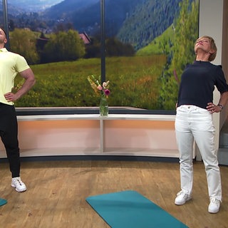 Physiotherapeut Florian Michel und Moderatorien Evelin König machen Rückenübungen