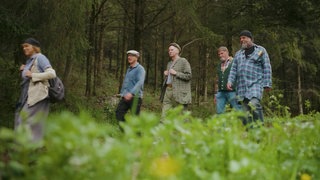 Fünf Personen laufen durch ein Waldgebiet.