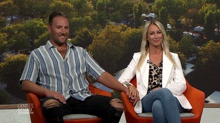 Sascha Bohner und Raffaela Scondo im Interview in der Landesschau. Sie sitzen auf roten Sesseln und halten Händchen. Die beiden haben sich auf einem Campingplatz kennengelernt und verliebt.