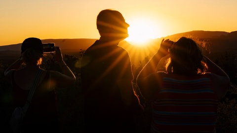 Menschen betrachten Sonnenuntergang