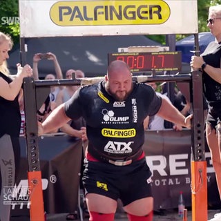 Denis Kohlruss trägt zwei Frauen auf einem Gestell auf seinen Schultern