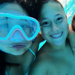 Kinder schauen unter Wasser in eine Kamera