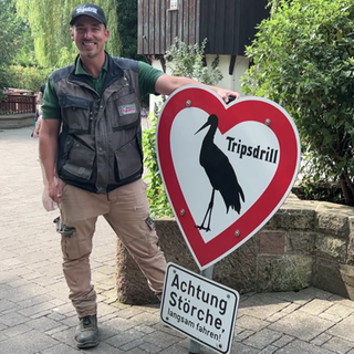 Ein Mann hält das wiederaufgetauchte Storchen-Schild von Tripsdrill in den Händen.