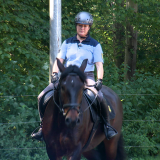 Polizeipferd Toni wird von Reiterin Ulrike Klein geritten und beide sind in voller Polizeiausrüstung zu sehen.