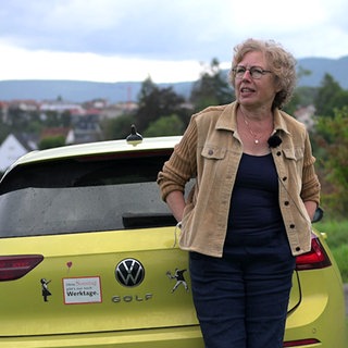 Die Hechingerin Regine Wagner steht vor ihrem Auto. Im Hintergrund ist Hechingen zu sehen.