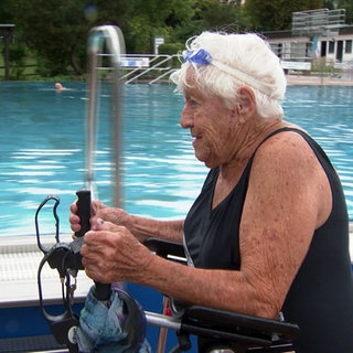 Die 101 Jahre alte Else Spiesberger geht fast jeden Tag im Freibad schwimmen. Sie trägt einen Badeanzug und nutzt eine Gehhilfe.
