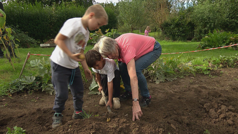 Rentnerpaar arbeitet mit Kindern im Garten.