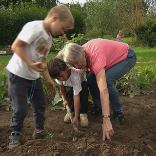Rentnerpaar arbeitet mit Kindern im Garten.
