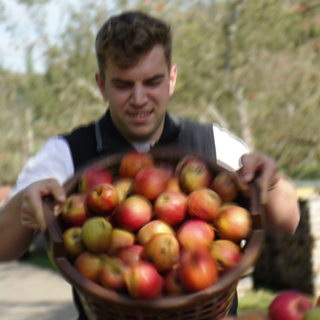 Paul Würtemberger steht mit einem Korb voller Äpfel.