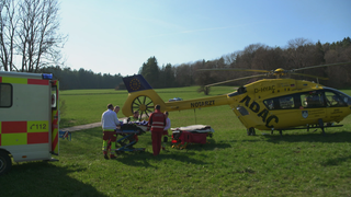 Die Heli-Retter transportieren einen verletzte Person in den Rettungshelikopter.