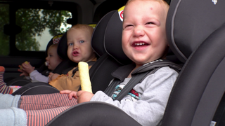 Drillinge sitzen auf der Rückbank in ihren Babyschalen im Auto.
