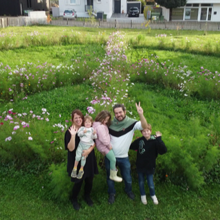 Familie Wald steht vor dem riesigen Peace-Zeichen in ihren Garten.
