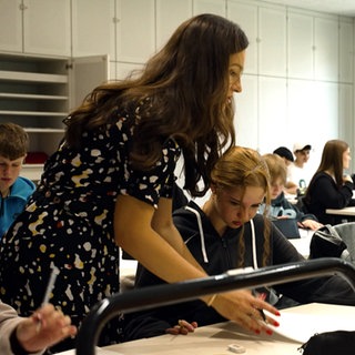Lehrerin steht zwischen Schülern einer Schulklasse der Oscar-Paret-Schule