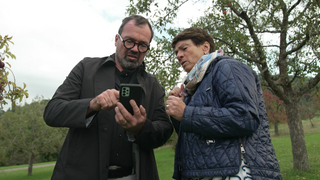 Sonja Faber-Schrecklein und Markus Hölz stehen auf einer Streuobstwiese in Mössingen und schauen auf ein Handy. 