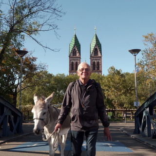Ernst König geht mit Esel Charly in Freiburg über eine Brücke