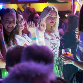 Viele Menschen in Dirndl und Leder feiern ausgelassen in einem Festzelt.