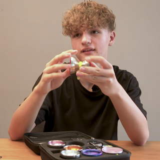 Yan Marosi sitzt an einem Tisch und zeigt ein Jo-Jo.