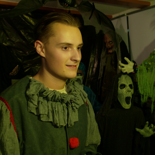 Julian Pyhrr steht in einem Raum, in dem gruselige Figuren stehen.