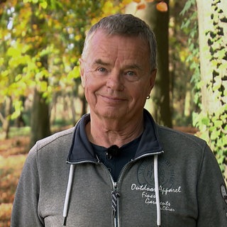 Ralf Wernicke steht vor herbtlich gefärbten Bäumen und lächelt in die Kamera.
