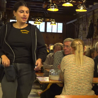 Gäste sitzen an vollen Tischen im Mostbesen Wolfenhausen, während eine Kellnerin die Bestellungen aufnimmt.