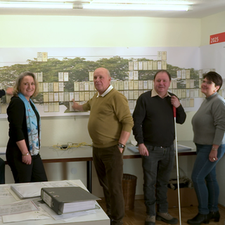 Eine Gruppe Ahnenforscher steht konzentriert vor einem großen Stammbaum.