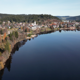 Blick aus der Drohne auf den ruhigen Titisee und die umliegende Stadt im Winter.