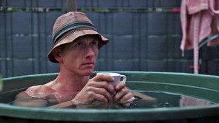 Ultraläufer Daniel Hernes sitzt in der Eistonne und hält eine Tasse in den Händen.