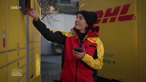 Postbotin räumt Packet in eine Packstation
