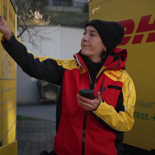 Postbotin räumt Packet in eine Packstation