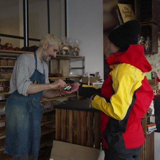 Paketbotin Nadine liefert Pakete in eine Bäckerei aus.