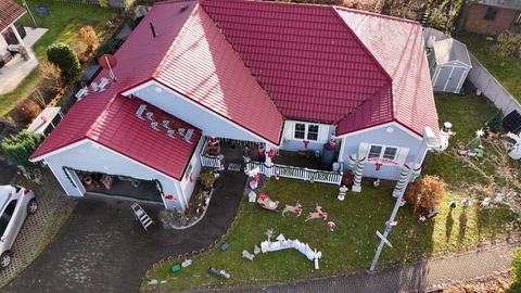 Ein amerikanisches Haus in Vogelperspektive. Es ist weiß, hat ein rotes Dach und ist weihnachtlich geschmückt.