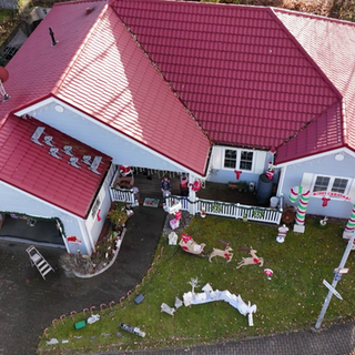 Ein amerikanisches Haus in Vogelperspektive. Es ist weiß, hat ein rotes Dach und ist weihnachtlich geschmückt.