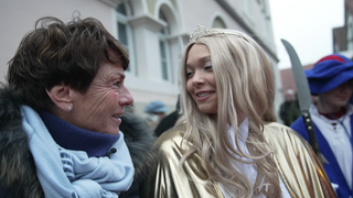 Sonja Faber-Schrecklein lächelt eine junge Frau an, die als Christkind verkleidet ist und eine Krone und einen goldenen Umhang trägt.