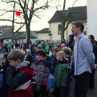 Sebastian Heinricht, der junge Schulleiter einer Grundschule steht mit vielen Kindern auf dem Pausenhof. 
