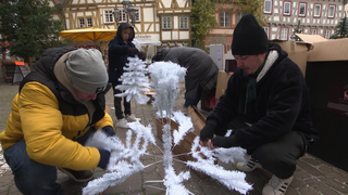 Oswin Nitschke breitet zusammen mit anderen Helfern einen weißen Kunstweihnachtsbaum aus. 