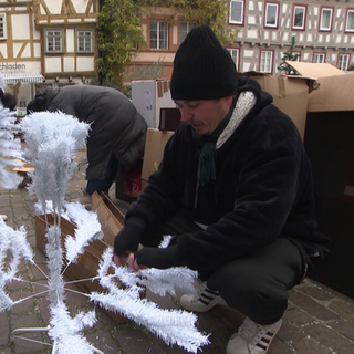Oswin Nitschke breitet zusammen mit anderen Helfern einen weißen Kunstweihnachtsbaum aus. 