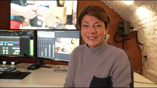 Sonja Faber-Schrecklein sitzt vor mehreren monitoren. Sie lächelt in die Kamera.