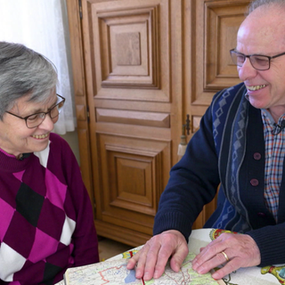 Karl-Heinz und Magdalena Schäfer sitzen gemeinsam am Tisch und betrachten eine Landkarte ihrer Fluchtroute.