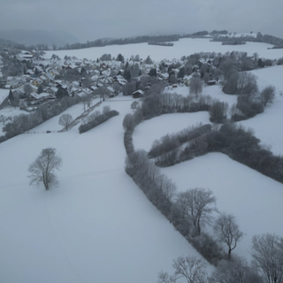 Luftaufnahme des verschneiten Orts Ochsenwang mit winterlicher Landschaft auf der Schwäbischen Alb.