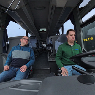 Ein Fahrlehrer begleitet einen Fahrschüler beim Steuern eines Busses.