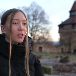 Die 13-jährige Naomi Klohn spricht in die Kamera, im Hintergrund ist der Dicke Turm der Esslinger Burg zu sehen.