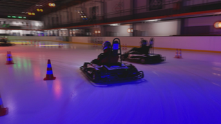 Personen sitzen in E-Go-Karts und rasen über die Eisfläche der Eishalle in Adelberg.