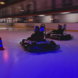 Personen sitzen in E-Go-Karts und rasen über die Eisfläche der Eishalle in Adelberg.
