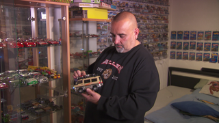 Franco Baldassarre steht vor seiner riesigen Modellauto-Sammlung und hält ein Auto in der Hand, umgeben von unzähligen bunten Miniaturen.