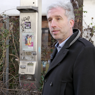 Boris Palmer steht neben einer alten Telefonzelle in Tübingen