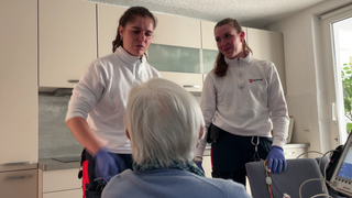 Zwei Notfallsanitäterinnen sprechen mit einer Seniorin