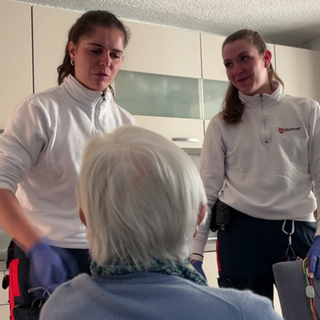 Zwei Notfallsanitäterinnen sprechen mit einer Seniorin