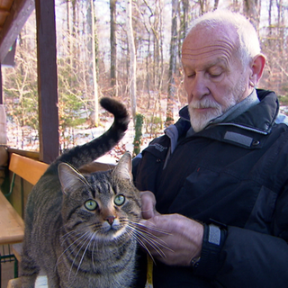 Eine Katze sind auf dem Schoss eines Besuchers im Friedwald Münsingen