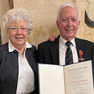 Helmut Schmidt hat das Bundesverdienstkreuz verliehen bekommen. Neben ihm steht seine Frau.